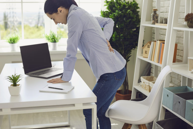 femme au bureau qui se tient les lombaires
